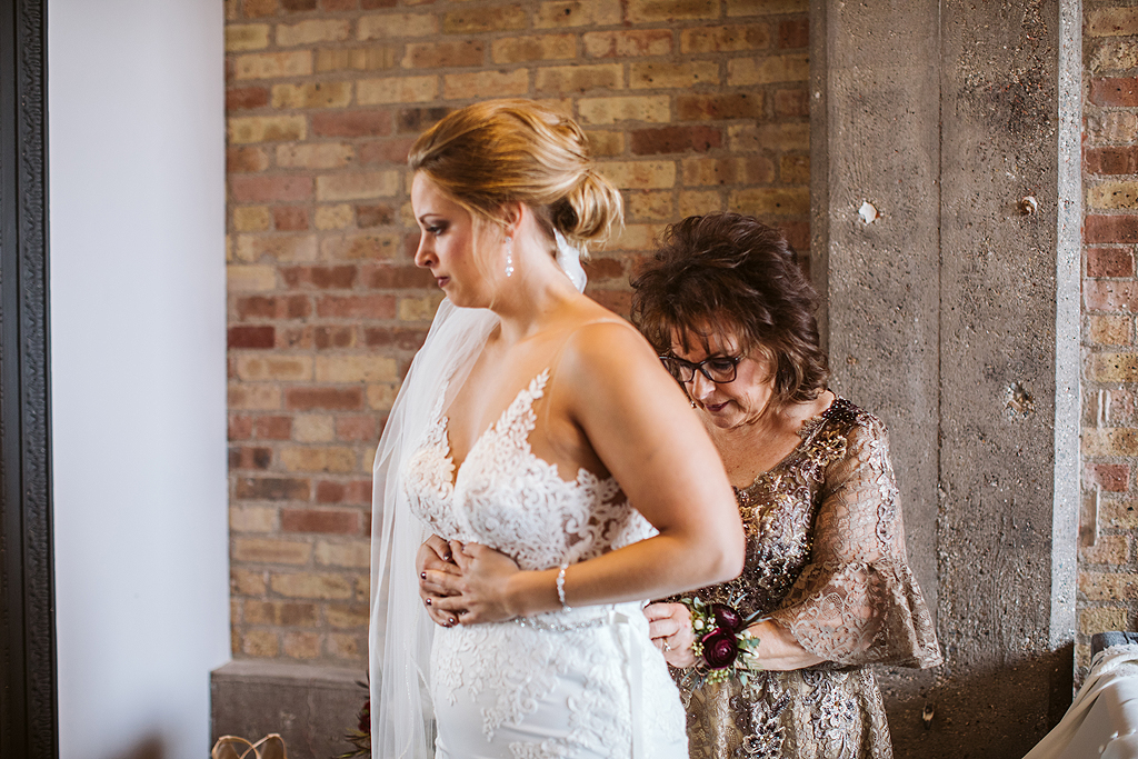 mother helping her daughter into bridal dress